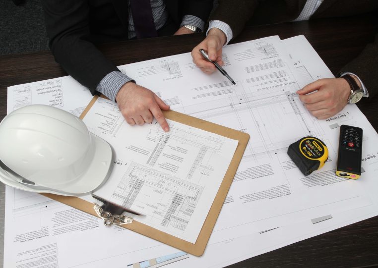 Flat lay showing individuals looking at building plans